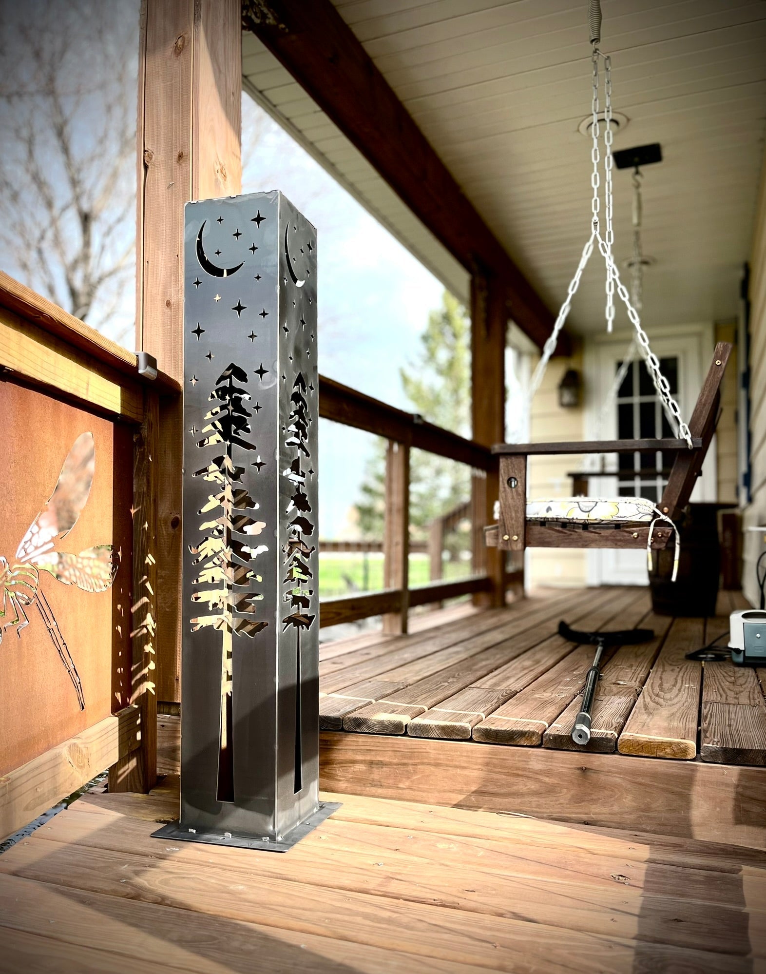 Decorative garden column with nature-themed design on a wooden deck.