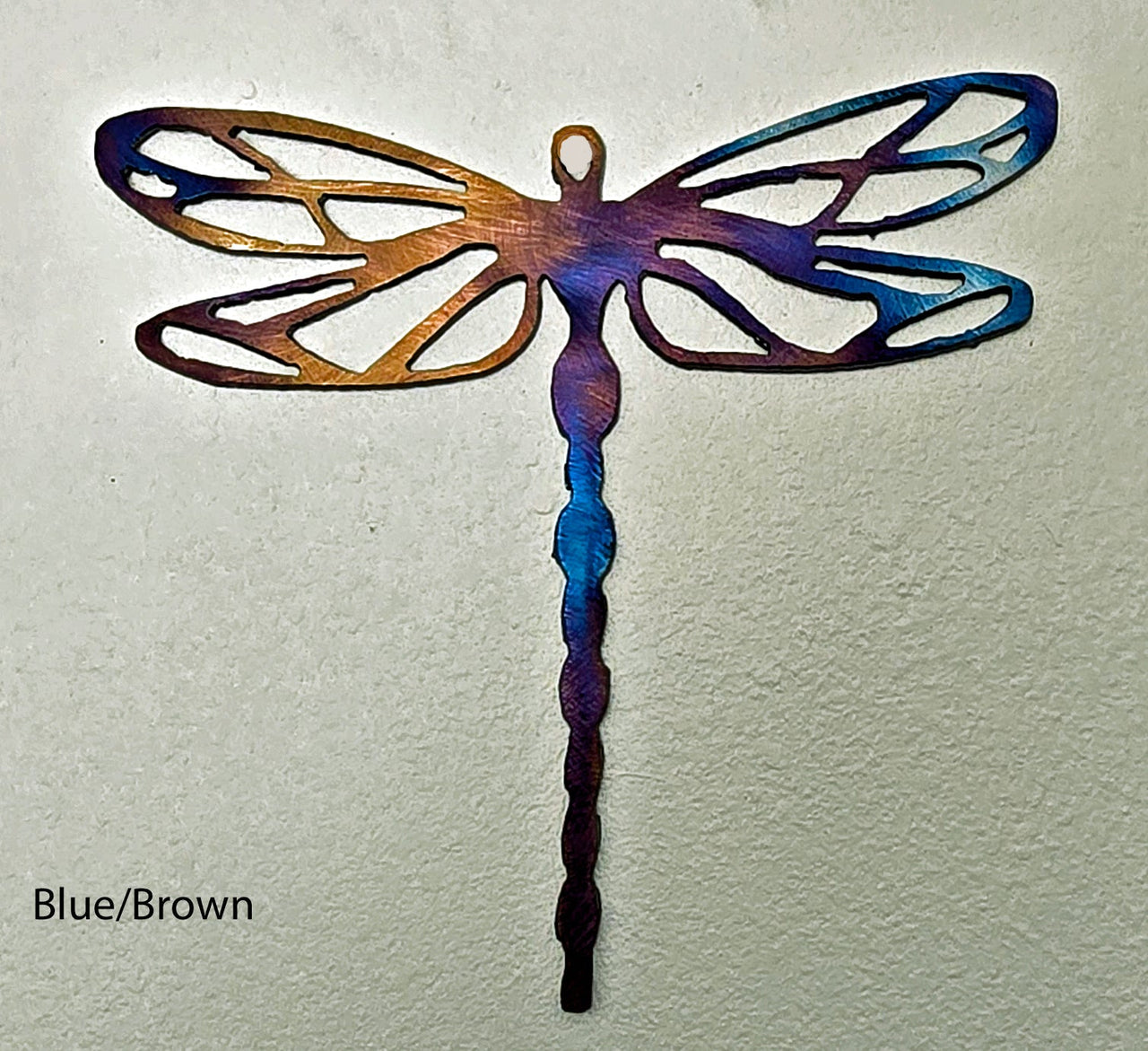 Metal dragonfly sculpture with blue and brown colors on a light gray background