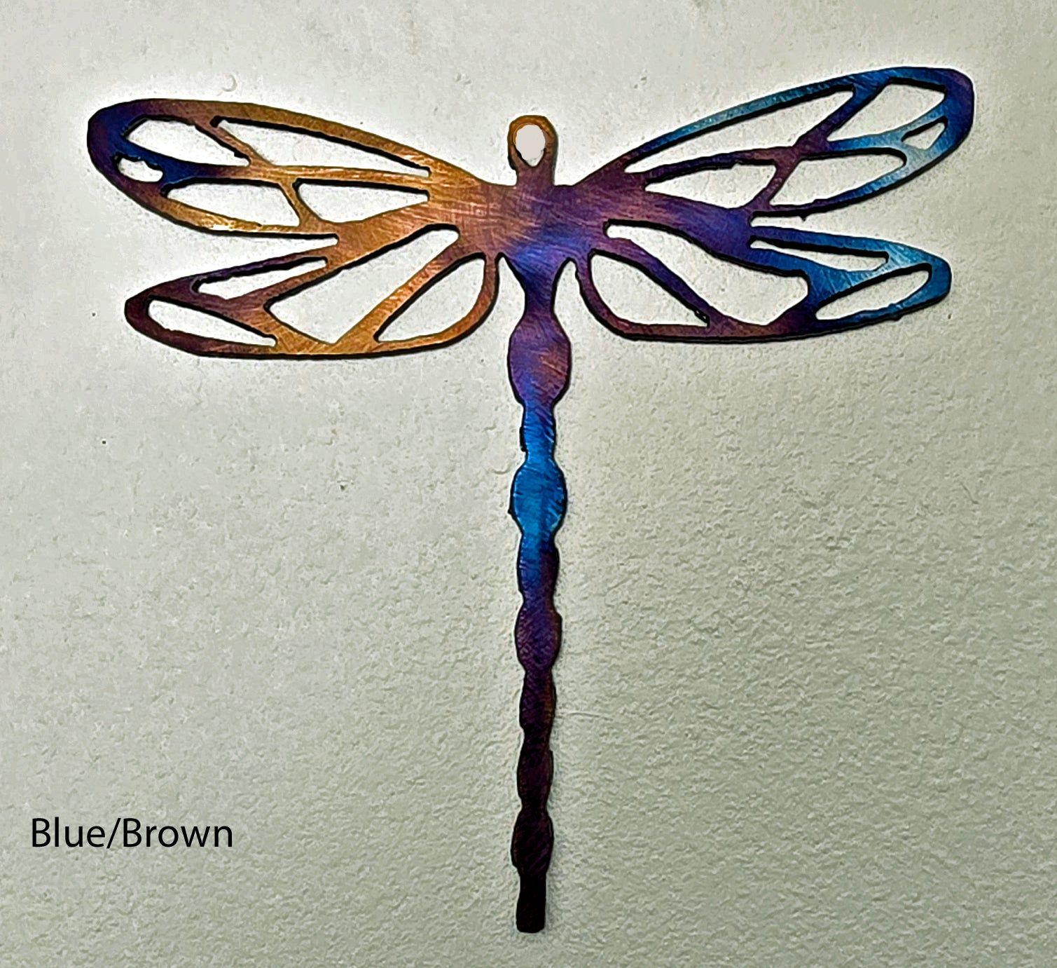 Metal dragonfly sculpture with blue and brown colors on a light gray background