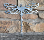 Metal dragonfly sculpture against a stone wall