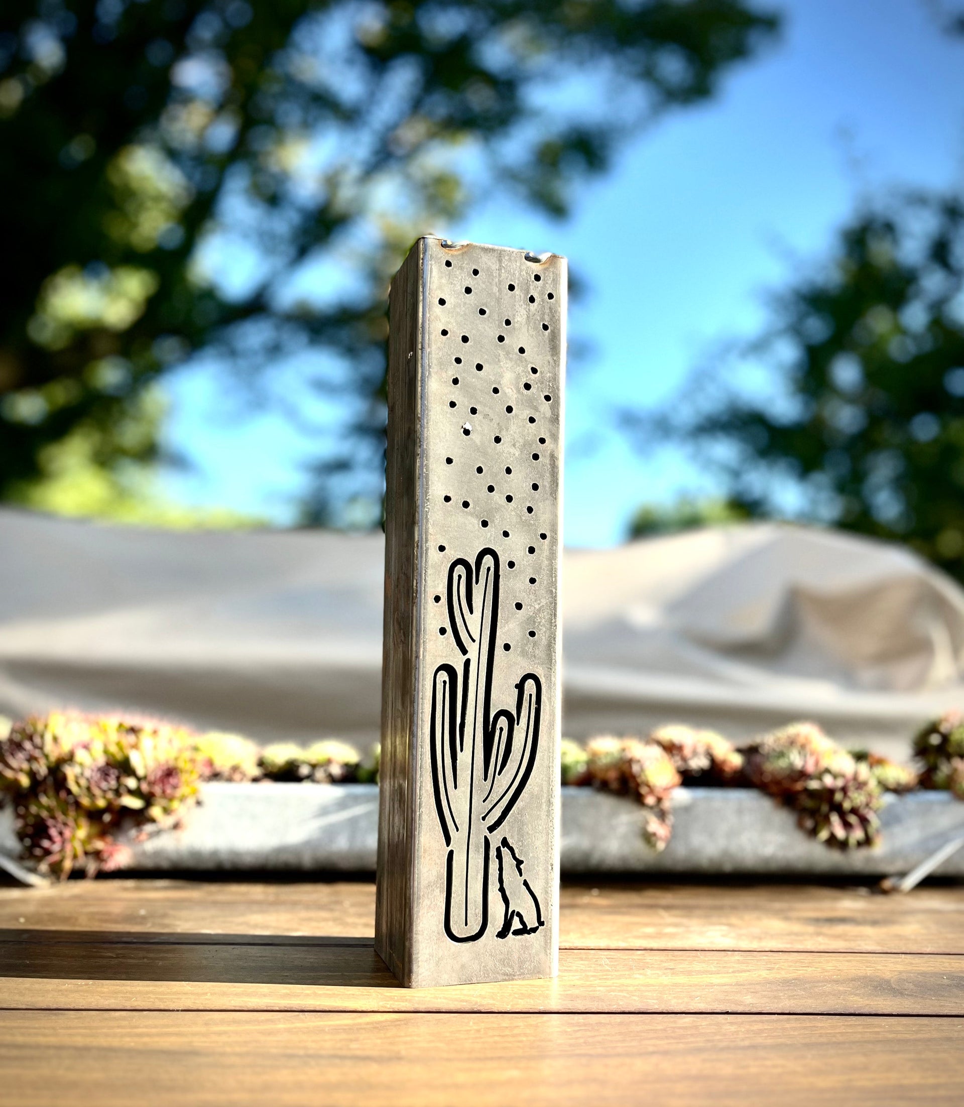 Metal Pillar with cactus design on a wooden surface outdoors