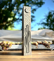 Decorative Metal Pillar with cactus design on a wooden surface outdoors.