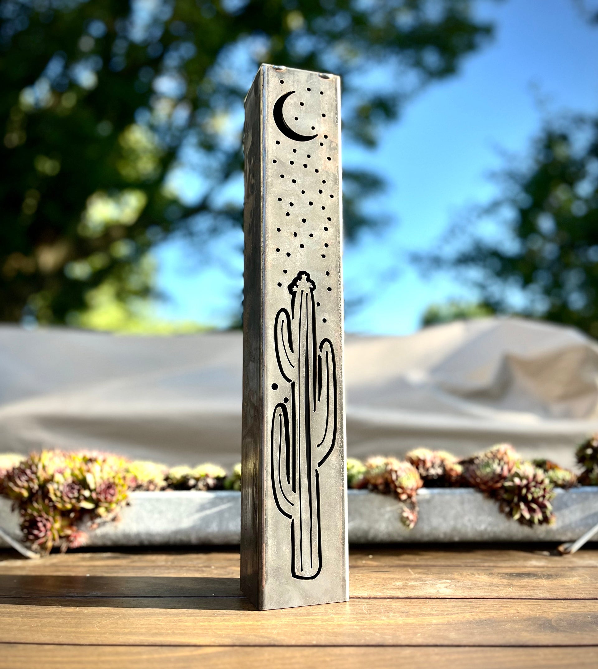 Decorative Metal Pillar with cactus design on a wooden surface outdoors.