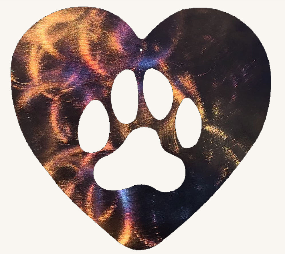 Heart-shaped metal cutout with a white paw print design on a multicolored background