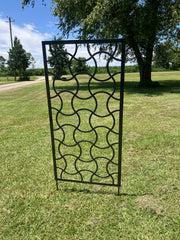 Decorative metal screen on grass with trees and sky in the background