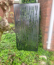 Decorative metal screen with wavy pattern in a garden setting