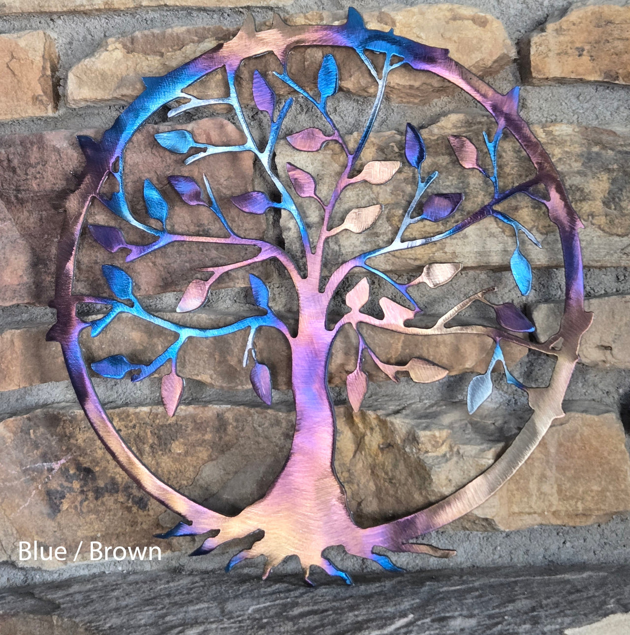 Metal tree sculpture with blue and brown colors on a stone wall