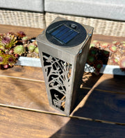 Solar-powered Vertical Garden Column fixture on a wooden surface with plants in the background