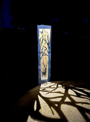 Decorative Vertical Garden Column with animal silhouette casting a shadow on a dark background