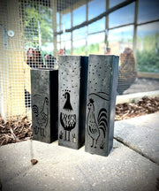 Three Garden Column Pillars with engraved rooster designs on a concrete surface.