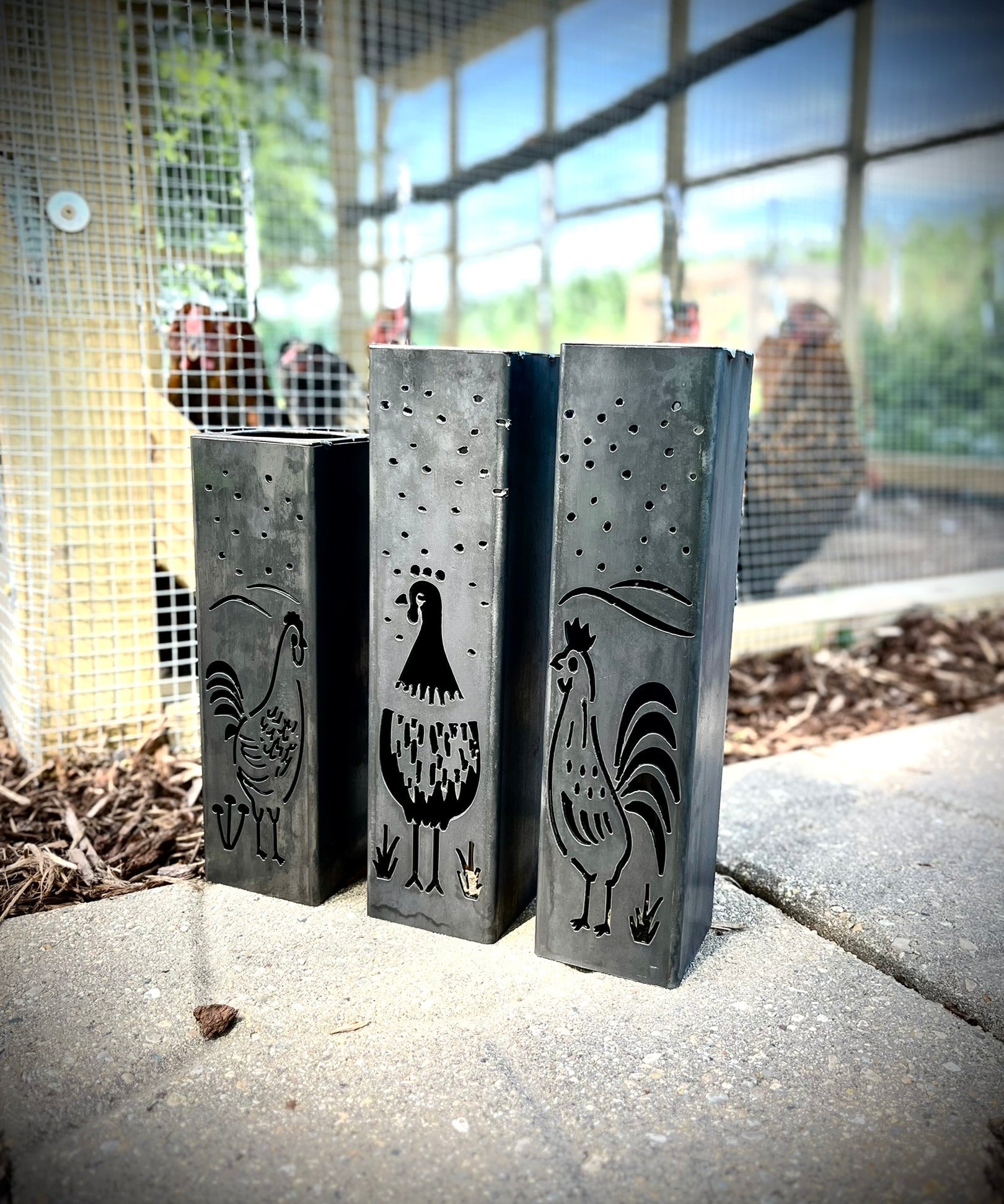 Three Garden Column Pillars with engraved rooster designs on a concrete surface.