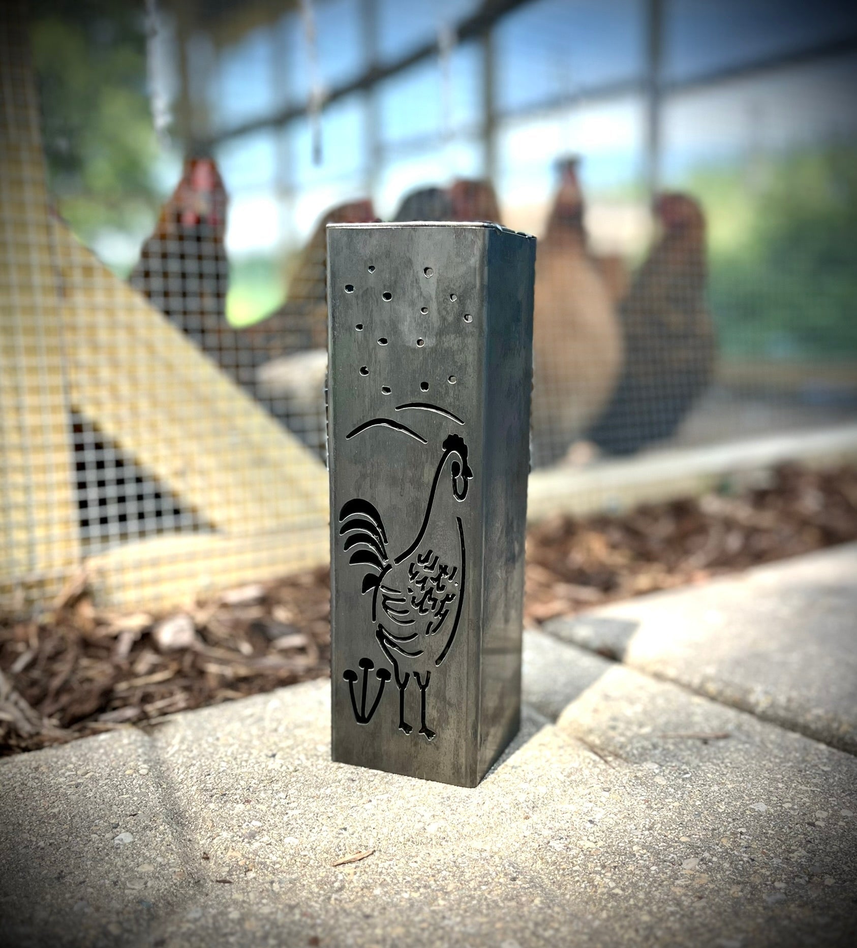 Garden Column Pillars with a rooster design on a concrete surface with chickens in the background