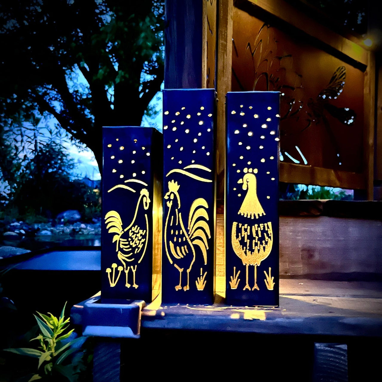 Garden Column Pillars with rooster designs on a wooden post at night.