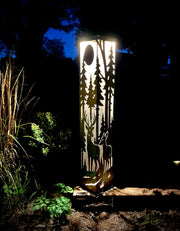 Decorative outdoor metal pillar with deer silhouette in a natural setting