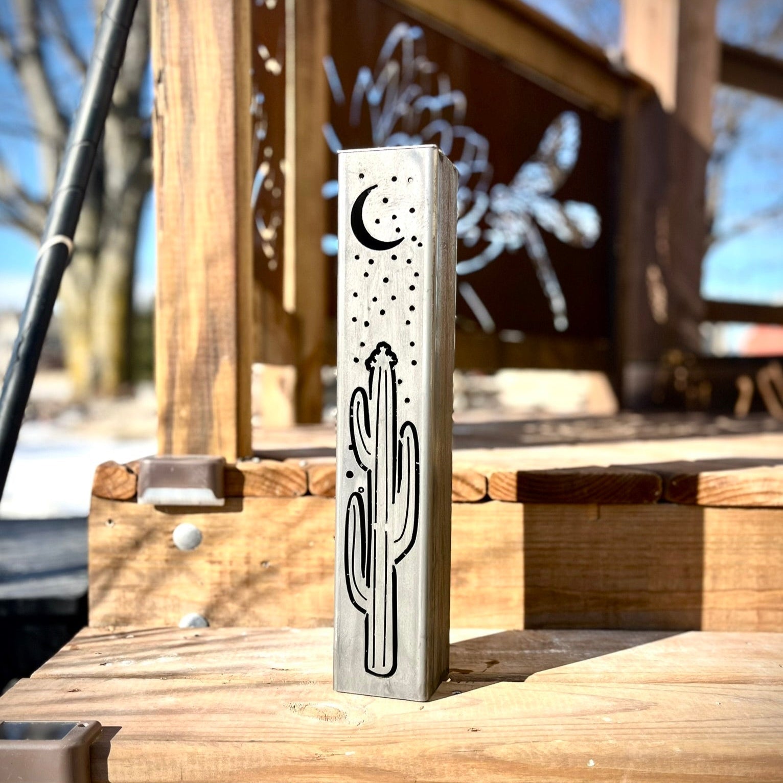 Metal Pillar with cactus and moon design on a wooden surface outdoors
