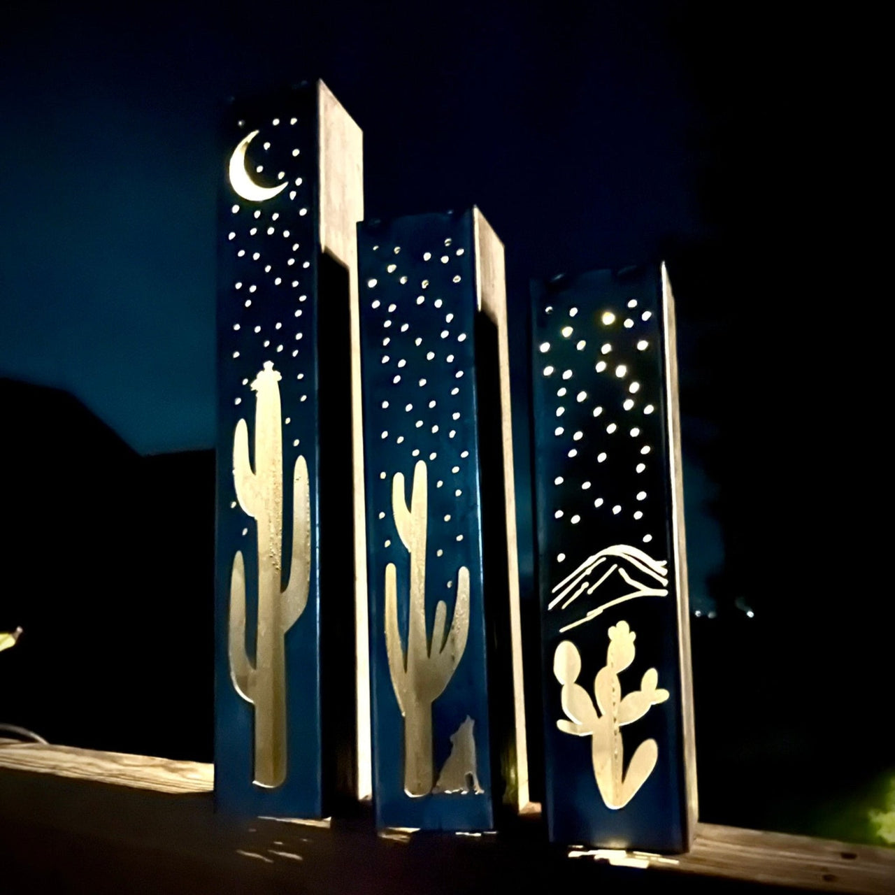 Ornamental garden pillars with cactus and mountain designs on a dark background