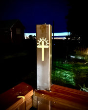 Decorative Garden Column Pillar fixture with cross design on a wooden surface at night.