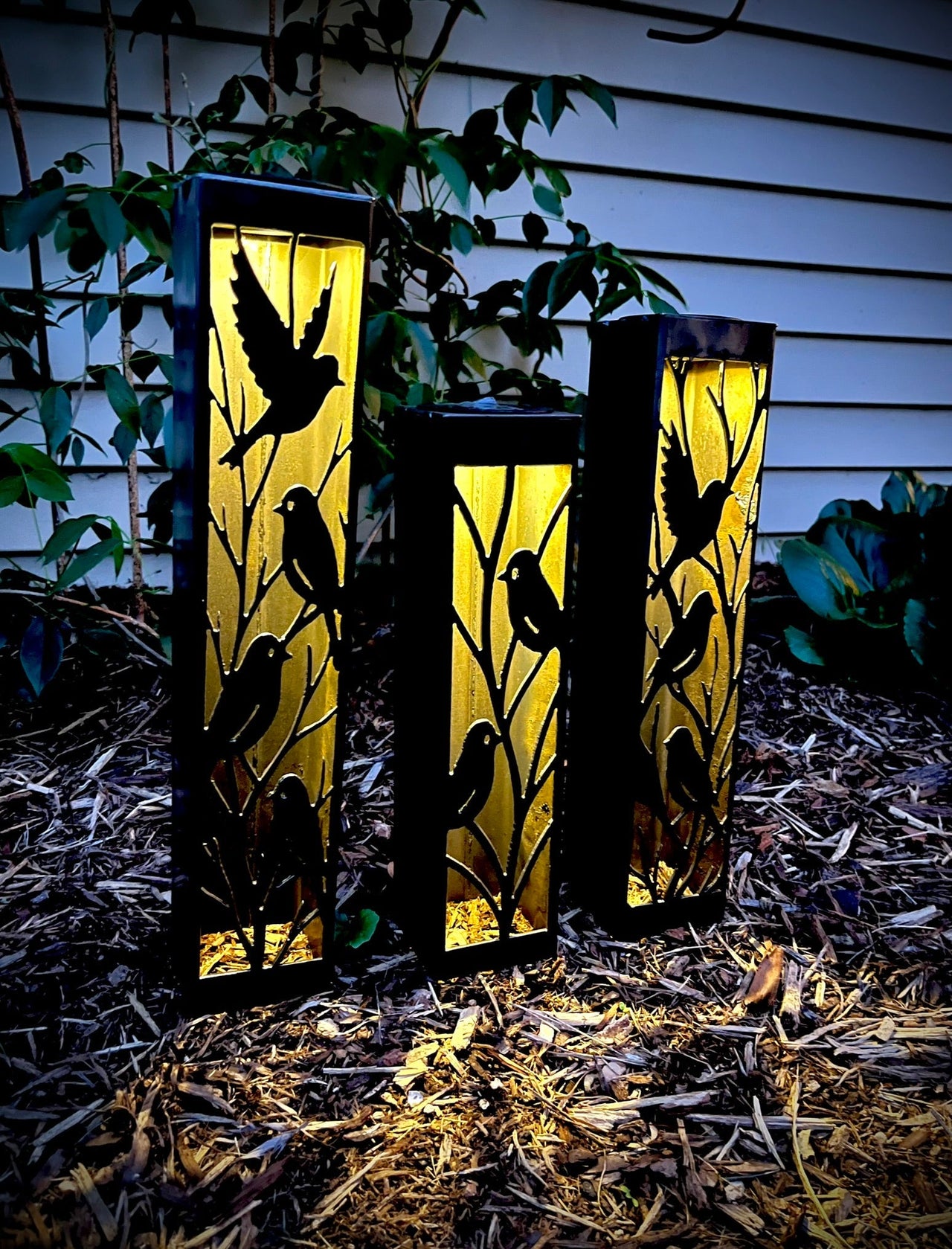 Three Outdoor Decorative Columns with bird designs on a natural ground surface.