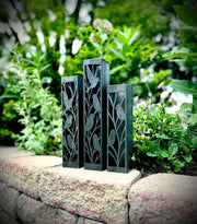 Outdoor Decorative Columns with bird patterns on a stone ledge with greenery in the background