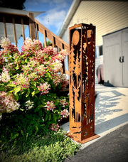 Decorative metal garden garden pillar with nature-themed cutouts in a garden setting.