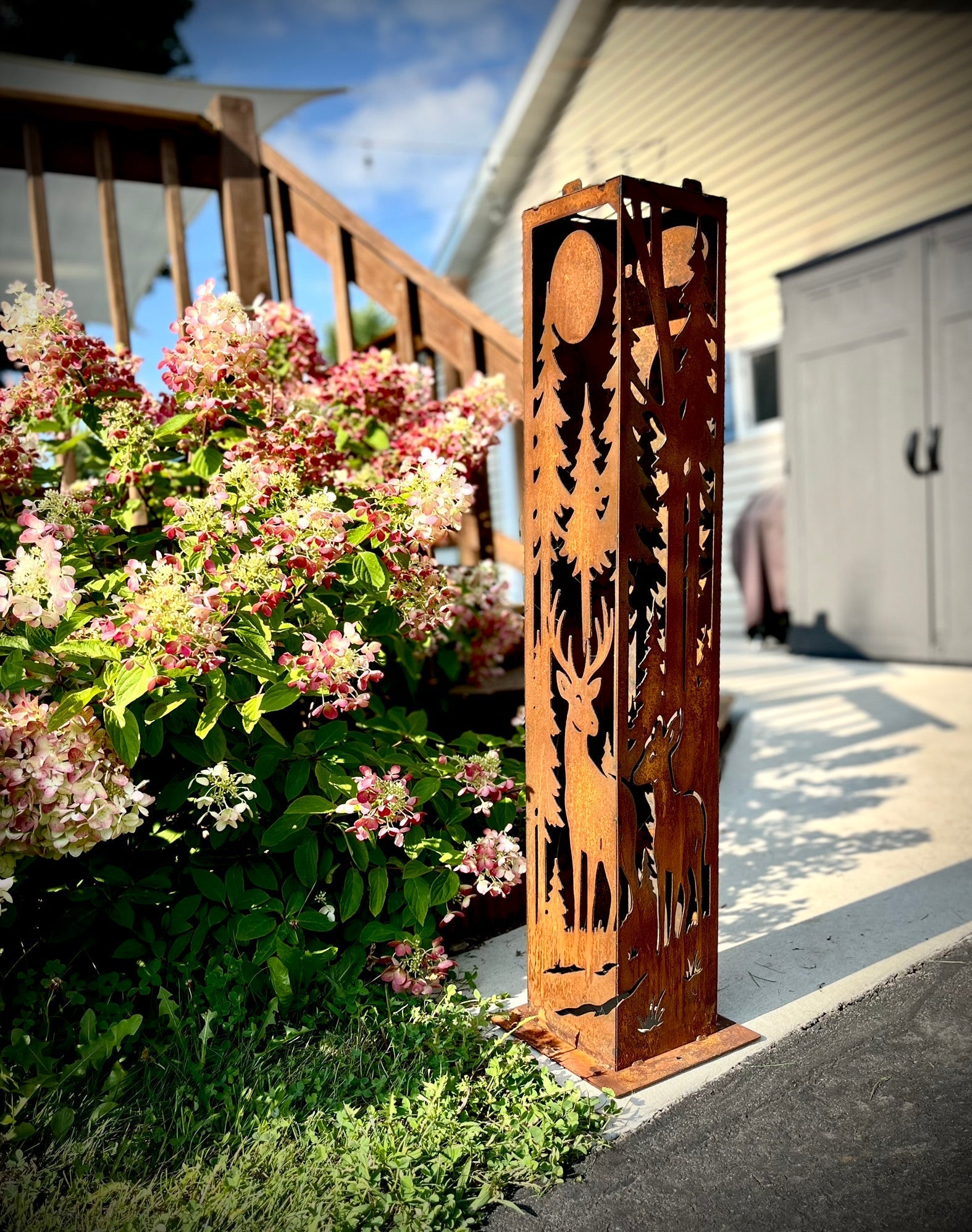 Decorative metal garden garden pillar with nature-themed cutouts in a garden setting.