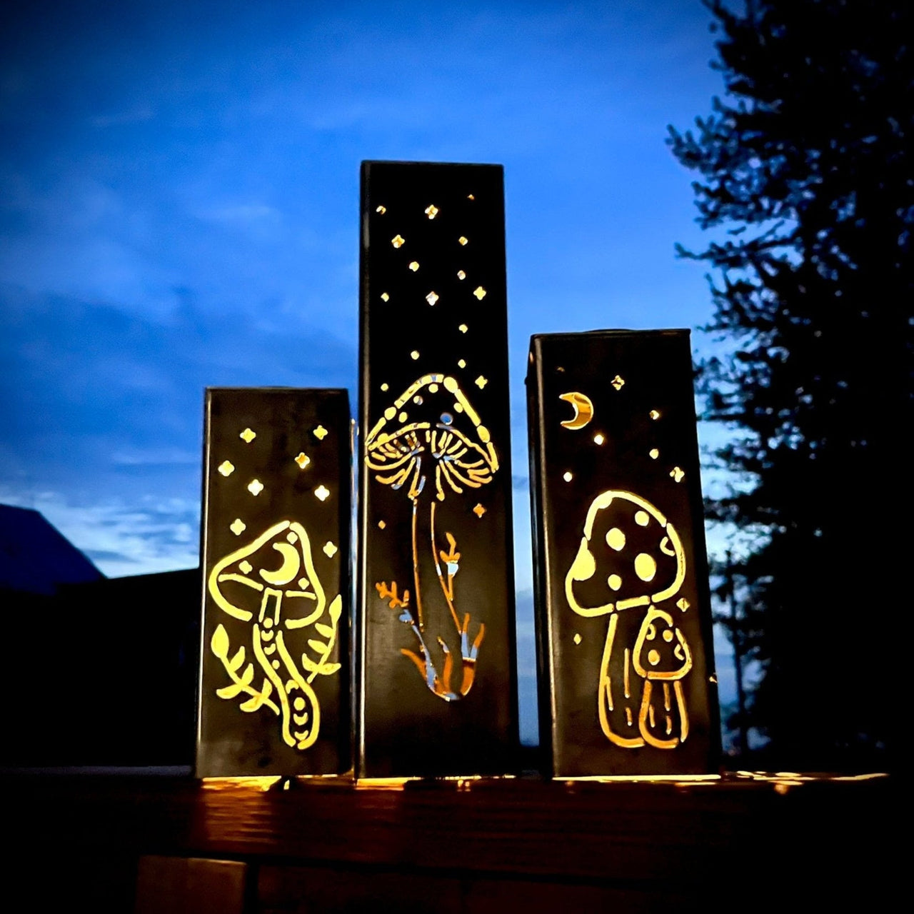 Three decorative mushroom Garden Pillars against a night sky with trees.