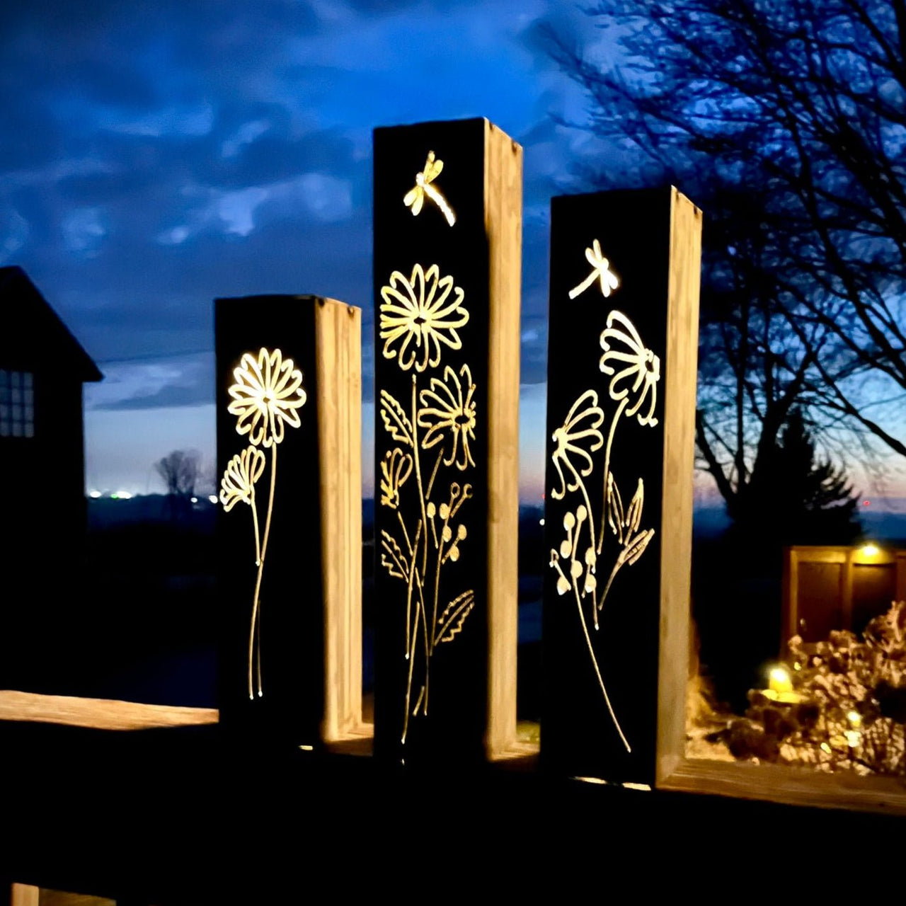 Outdoor Decorative Pillars with floral cutouts illuminated at night outdoors.