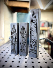Three garden column pillars with fish designs on a pegboard background