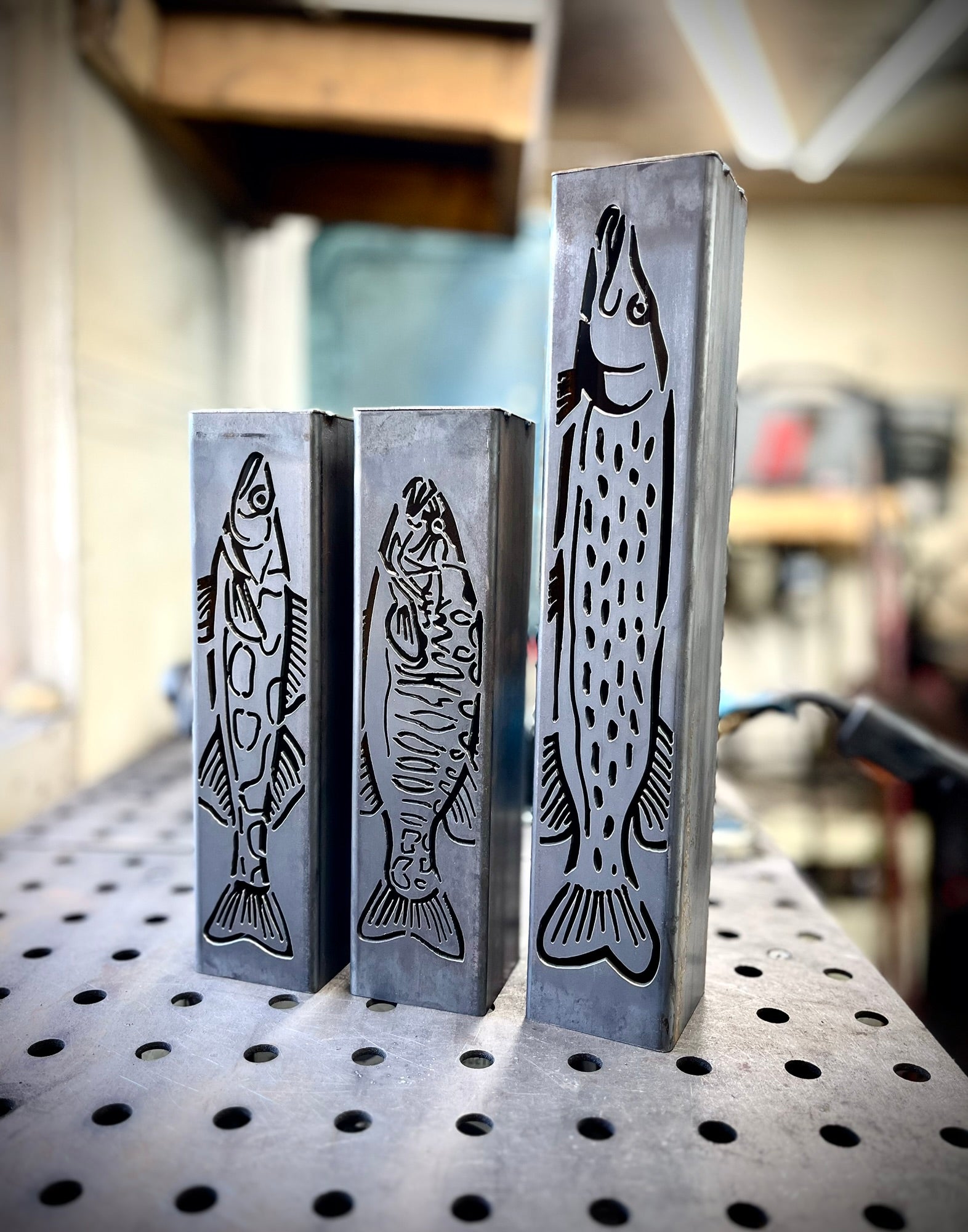 Three garden column pillars with fish designs on a pegboard background