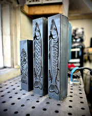 Metal garden column pillars with fish design on a workshop table