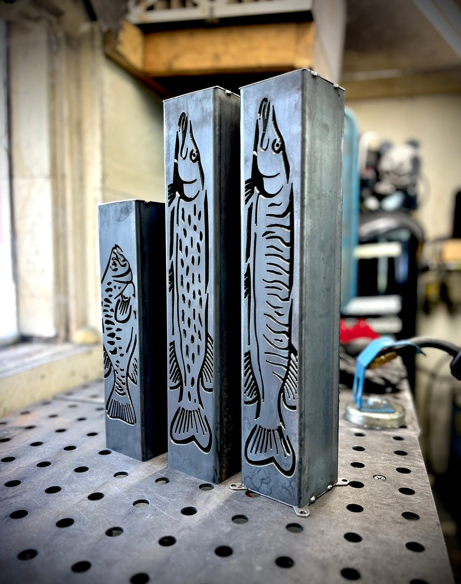 Metal garden column pillars with fish design on a workshop table