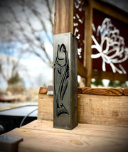 Metal garden pillar with fish design on a wooden surface outdoors