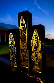 Decorative outdoor garden column pillarswith fish designs on a dark background