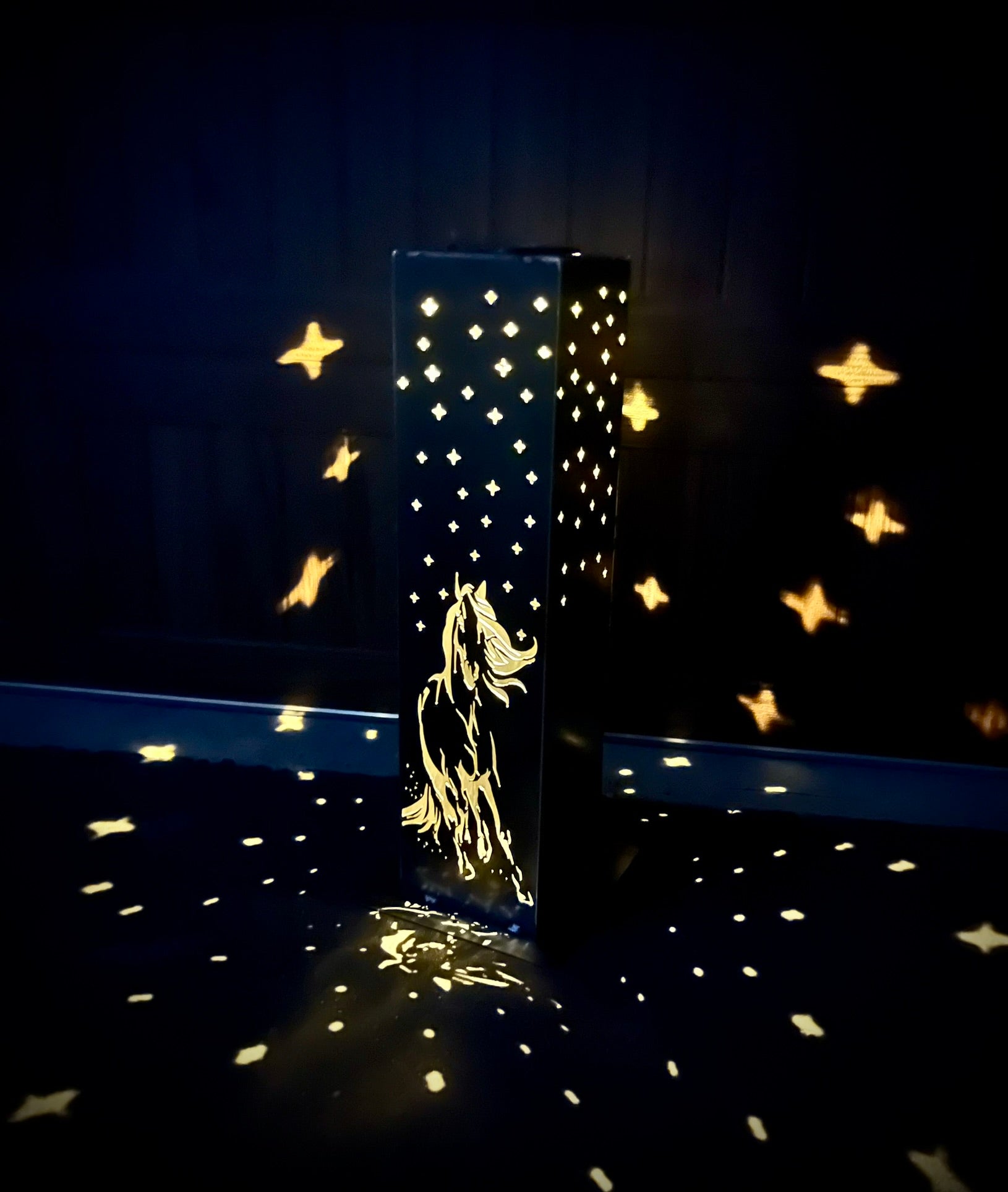 Decorative Garden Pillar with star patterns and a horse design on a dark background