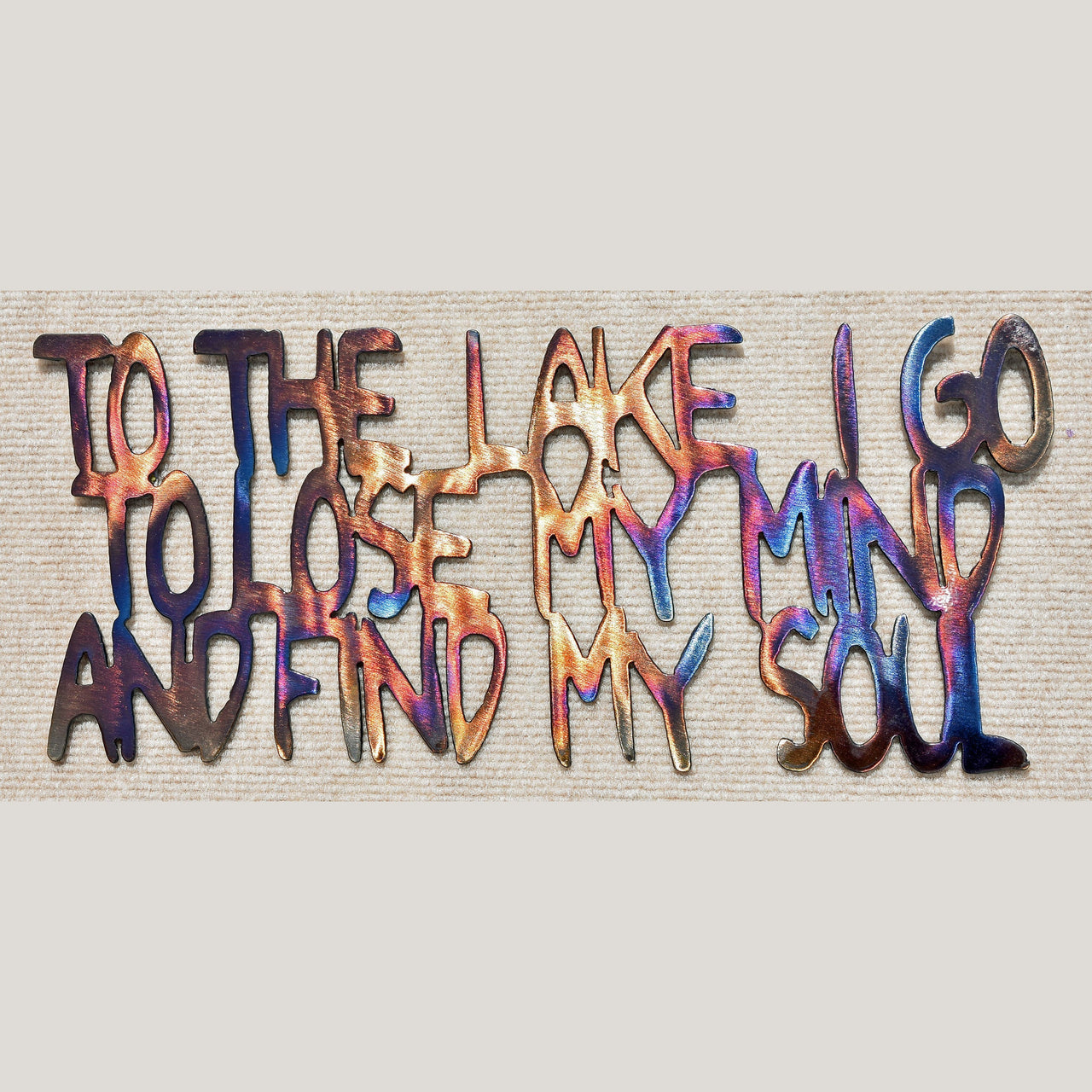 Colorful metal wall art with text on a textured background