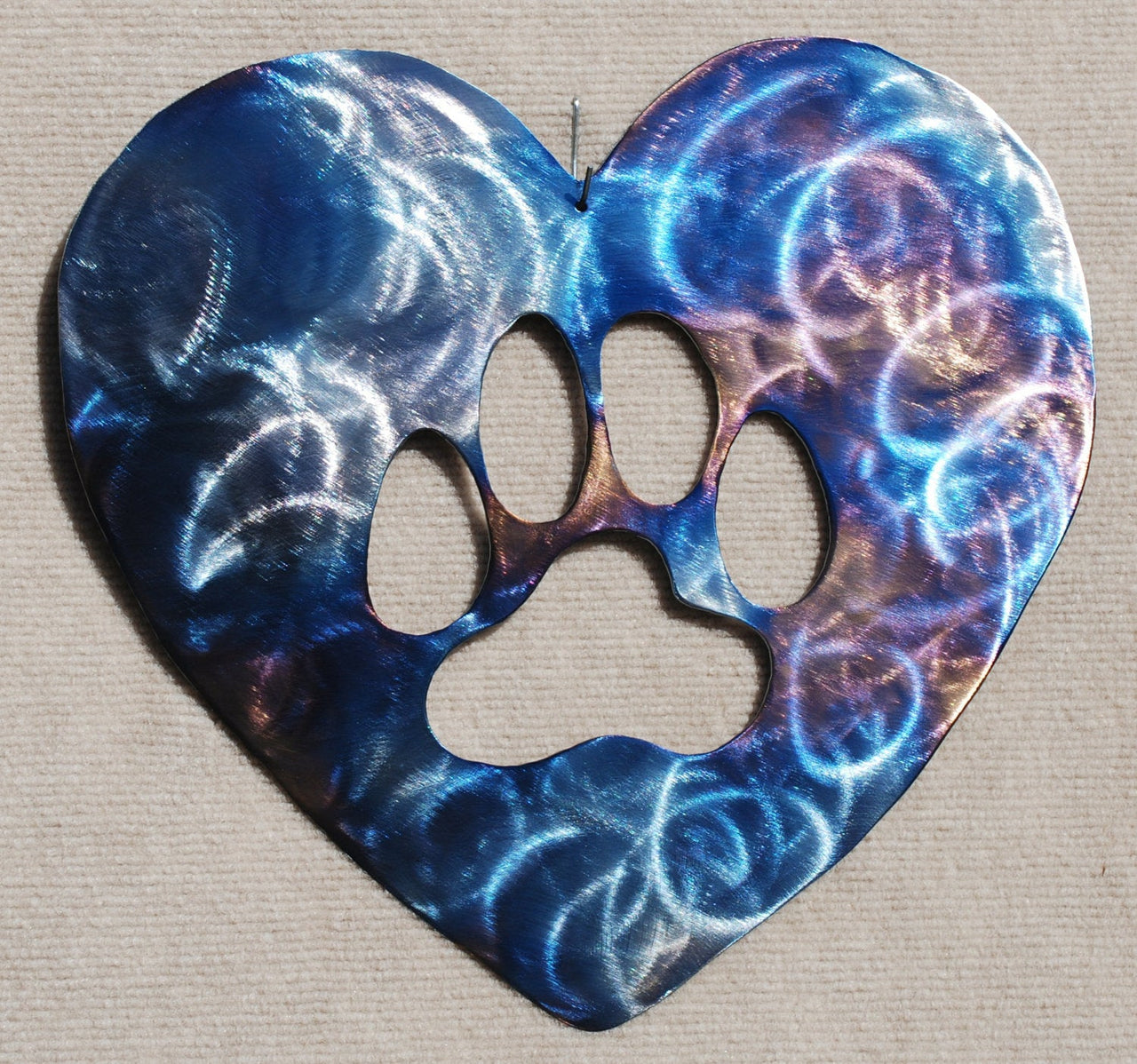 Heart-shaped decorative item with a paw print cutout featuring blue and purple abstract patterns on a beige background.
