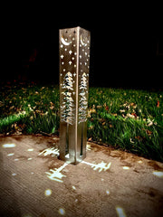 Decorative outdoor garden column with engraved designs on a grassy area at night.