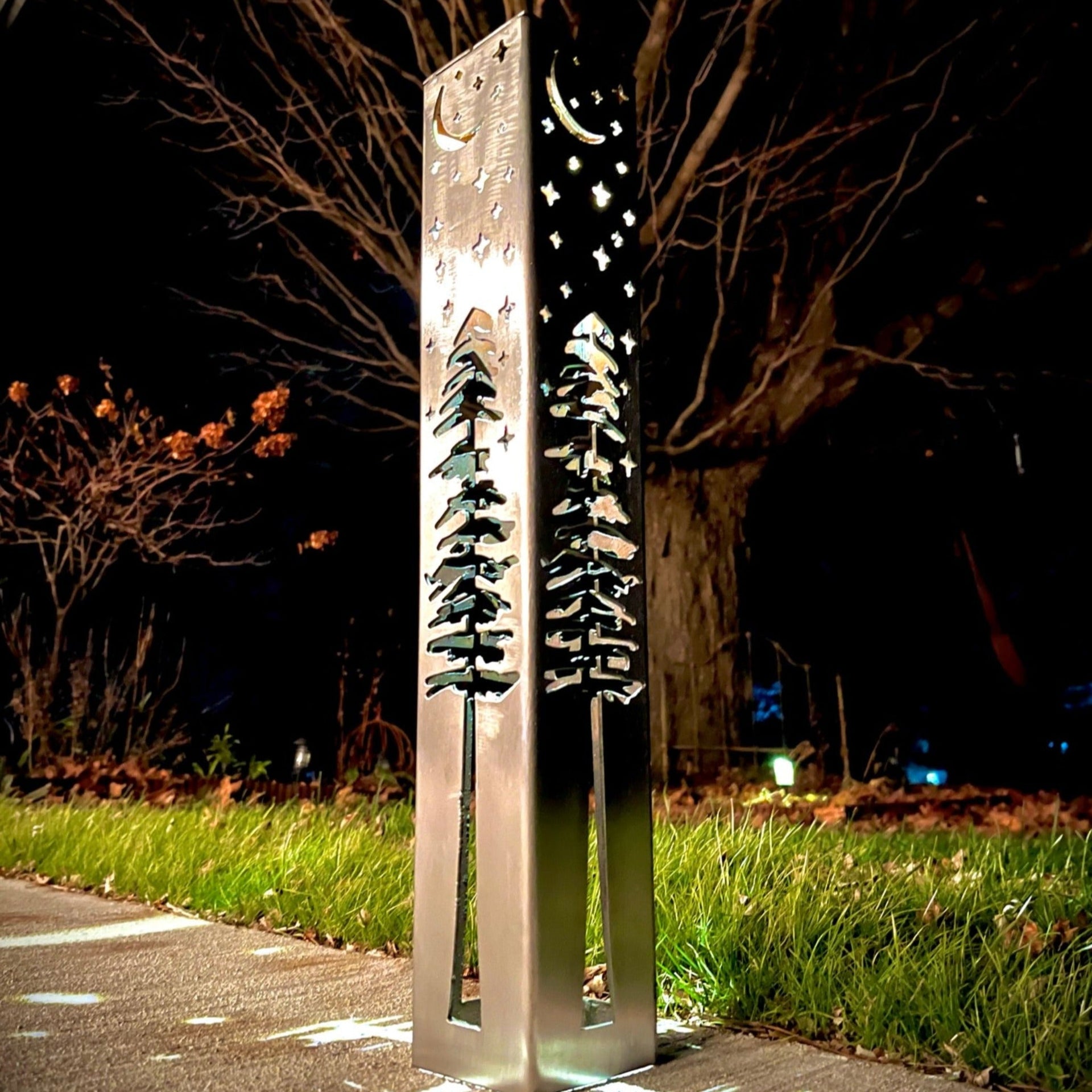 Decorative outdoor garden column with celestial design on a dark night.