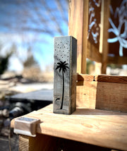 Outdoor garden column with palm tree and moon designs on a wooden surface. palm tree design on a wooden surface outdoors
