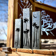 Outdoor garden columns with palm tree and moon designs on a wooden surface.