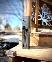 Outdoor garden column with palm tree and moon designs on a wooden surface.with palm tree and moon design on a wooden surface outdoors.