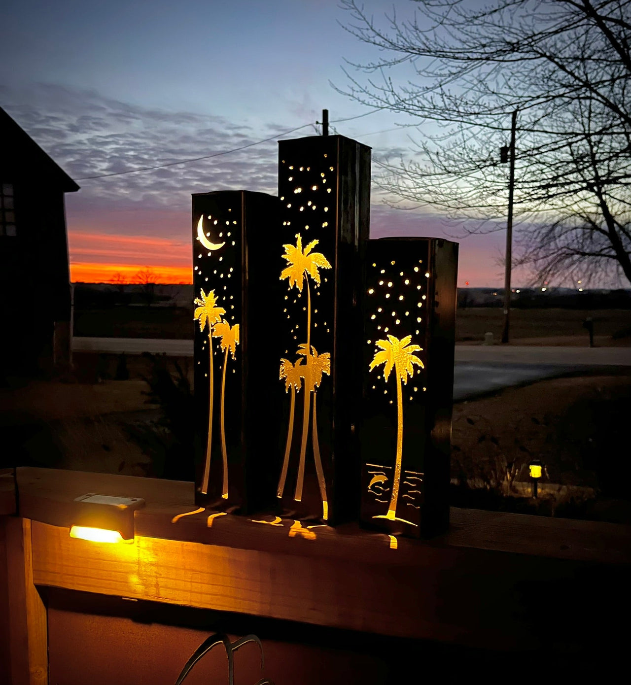 Outdoor garden columns with palm tree and moon designs on a wooden surface. with palm tree and moon designs, glowing in the evening.