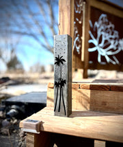 Outdoor garden column with palm tree and moon designs on a wooden surface. with palm tree design on a wooden surface outdoors