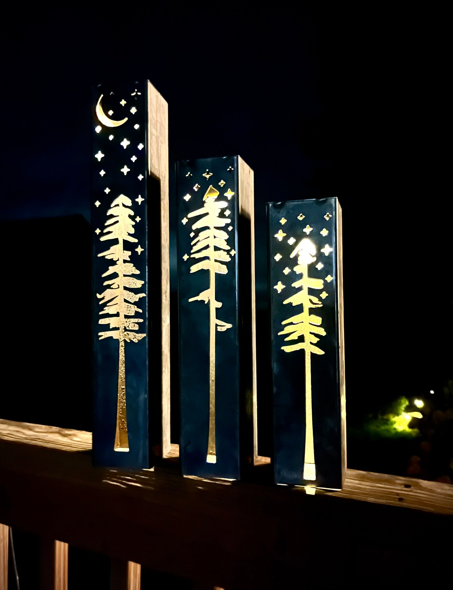 Decorative metal pillars with tree and moon design on a dark background