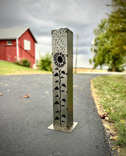 Decorative metal Garden Column Pillar with floral design on a road next to a red building.