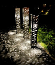Decorative Garden Column Pillar with floral patterns casting shadows on a pathway at night.
