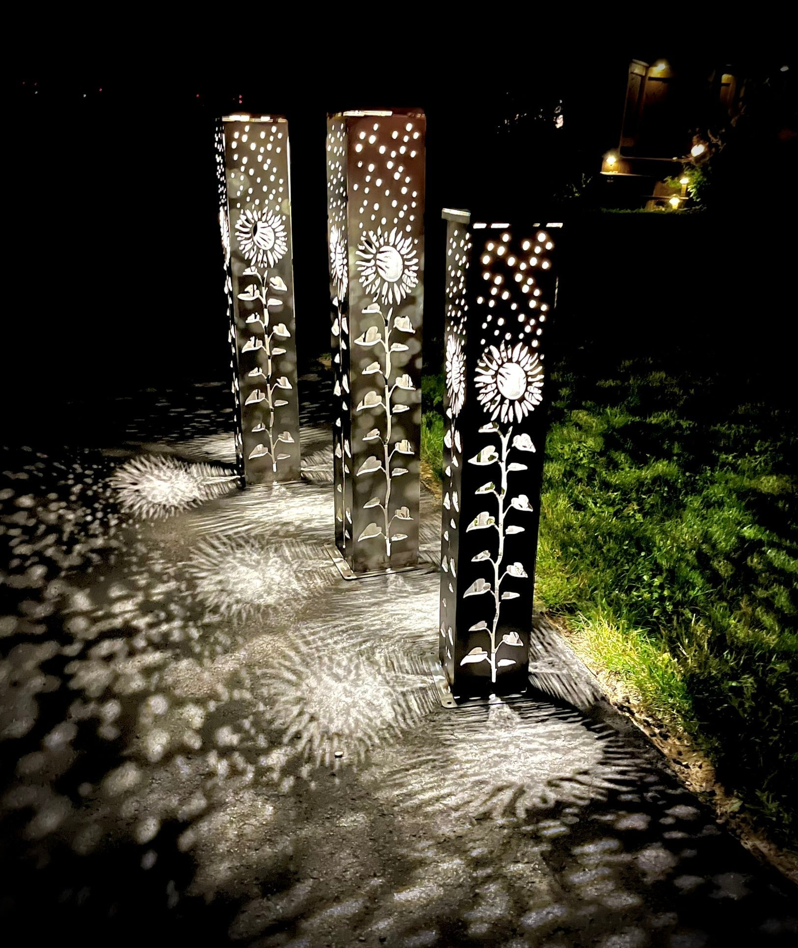 Decorative Garden Column Pillar with floral patterns casting shadows on a pathway at night.